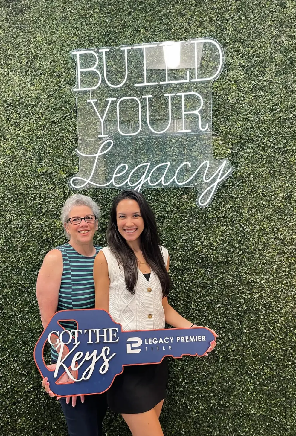 Happy clients at the Build Your Legacy neon wall